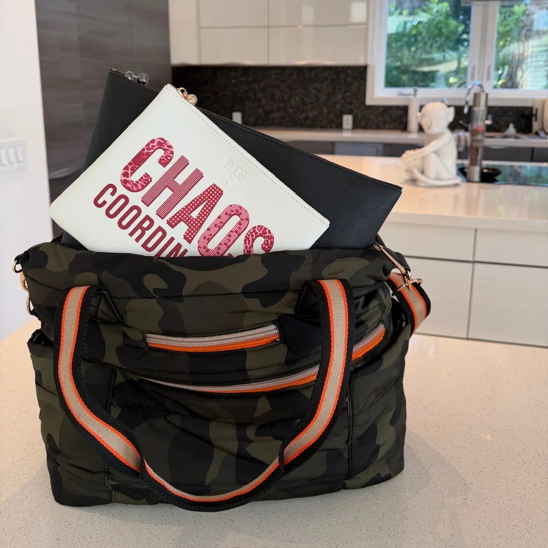 White #4 Chaos Coordinator pouch tucked into a camo weekender on a kitchen counter
